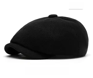 Detail of black wool blend newsboy cap showing textured twill weave and button top
