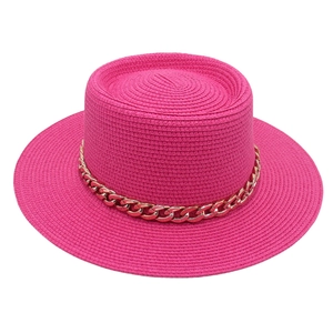 Detailed texture of rose red straw boater hat featuring a decorative gold chain