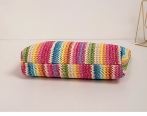 Detailed macro view of vibrant rainbow woven texture on a flat rectangular handbag