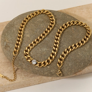 Elegant gold necklace with sparkling white zircon stone on textured stone props