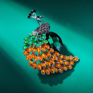 Detailed close-up of a vintage peacock brooch with green gemstones and sparkling rhinestones