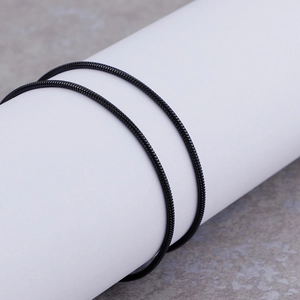 Detail showing high-polish black snake bone chain texture on minimalist metal necklace