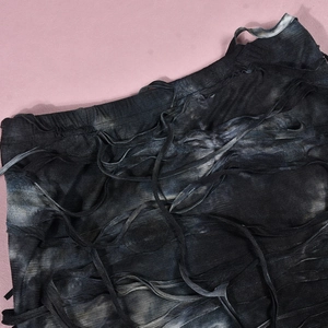 Detail of tie-dye distressed fabric with decorative ribbons and tassel fringe elements