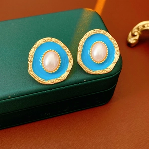 Macro shot of vintage gold earrings with blue enamel finish and centered pearls