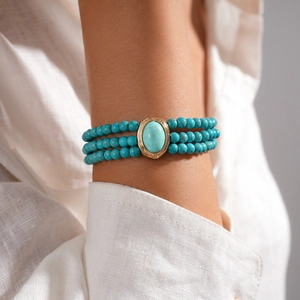 Detail showing three-layer turquoise beaded bracelet with large oval stone on model wrist