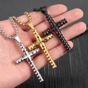 Gros plan de pendentifs croix cylindriques en argent, or et noir avec détails texturés