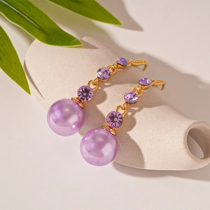 Close-up of vintage violet faux pearl earrings with purple rhinestones and gold hooks