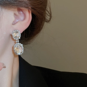 Macro view of silver drop earrings featuring large oval and square crystals with rhinestones