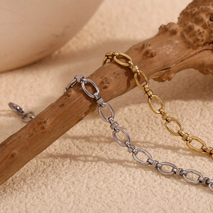 Close-up of gold and silver minimalist cross-buckle bracelets on a natural wood branch