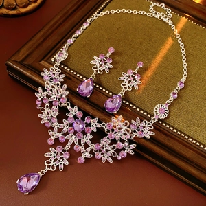 Macro shot of silver floral necklace and earrings set with purple waterdrop rhinestones