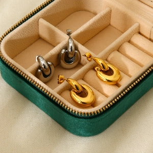 Macro shot of gold and silver U-shaped stainless steel earrings in green velvet box