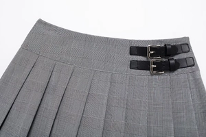 Détail de la jupe-culotte plissée à carreaux gris avec doubles boucles noires décoratives