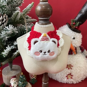 Detail of red and white knitted pet bib featuring a plush Christmas bear character