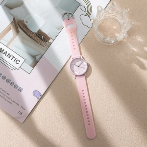 Pink silicone strap women's watch with white dial on a table with magazine and props