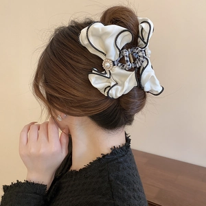 Detail of elegant cream fabric bow hair claw with pearl accents on a woman's hair