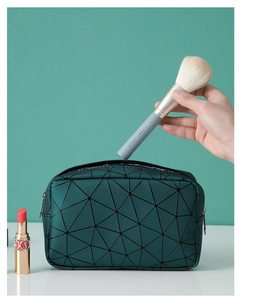 Detail of dark green cosmetic bag featuring geometric patterns and soft fabric texture