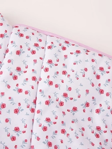 Close-up of white cotton fabric featuring pink rosebud prints and pink hemmed edges