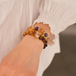 Detail of three-layer beaded bracelet featuring tiger eye and amethyst stones on a wrist