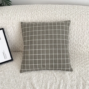 Detail of taupe checkered cotton linen pillowcase on a soft white teddy fleece sofa
