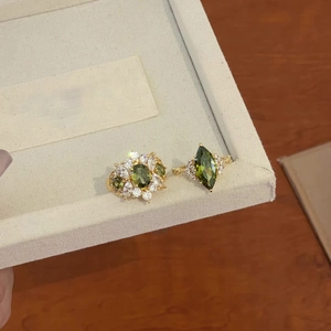 Detailed macro view of 14k gold plated rings with olive green zircons on a beige box