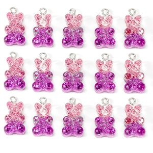 Flat lay of pink gradient gummy bear resin pendants with glitter for DIY jewelry making