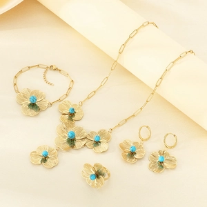 Detail of vintage gold flower jewelry set with turquoise stone on soft beige silk