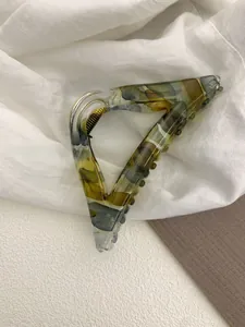 Detailed close-up of a triangular tortoise shell hair claw with marble texture and gold spring