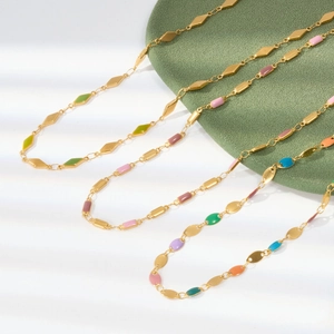 Detailed close-up of three gold titanium necklaces with colorful geometric enamel shapes