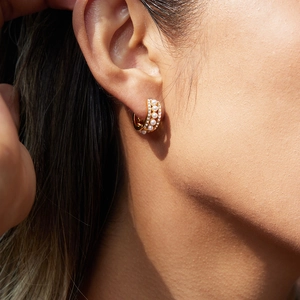 Eleganti orecchini a cerchio dorati con perle e strass scintillanti indossati da una modella