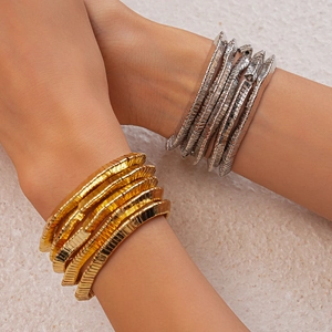 Macro shot of stacked gold and silver geometric industrial bracelets on model