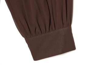 Detailed macro view of dark brown chiffon dress cuff with pleated elastic shirring details