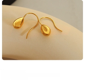 Macro detail of elegant gold-plated teardrop earrings with high-polish mirror finish