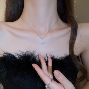 Close-up of light blue square gemstone necklace and ring set with silver chain and diamonds