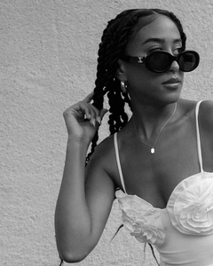 Detailed view of white floral camisole top paired with retro oval sunglasses and gold jewelry
