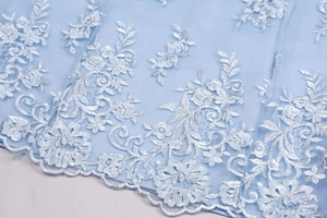 Close-up of light blue mesh fabric featuring exquisite 3D lace floral embroidery details