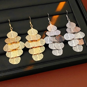 Close-up of layered metallic leaf tassel earrings in gold and silver finish