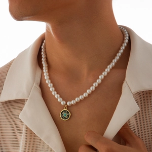 Men's pearl necklace with a sunburst turquoise pendant worn on a male model's neck