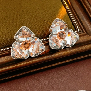 Detailed view of silver flower earrings with orange crystals on a vintage frame