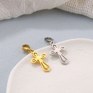 Close-up of gold and silver hollow cross pendants with lobster clasps on a ceramic plate