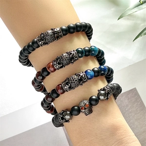 Detail of stacked punk beaded bracelets with skull and crown charms on male wrist