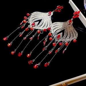 Detailed close-up of vintage tassel earrings with silver filigree and red crystals