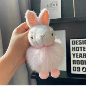 Detail shot of a plush bunny keychain with soft pink ears and a fluffy white face