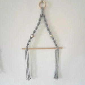 Detail of grey macrame wall hanging tissue holder with wooden rod and cotton fringe