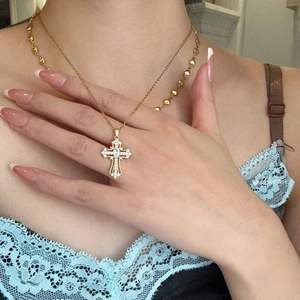 Detalle de un colgante de cruz vintage en oro con circonitas sobre una cadena fina