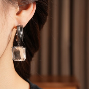 Gros plan de boucles d'oreilles carrées en verre en forme de C portées par un mannequin