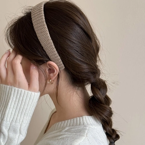 Detail view of a brown knitted headband worn on braided hair showing soft fabric texture