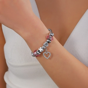 Detail of silver crown charm bracelet with pink crystal beads and heart pendant on wrist