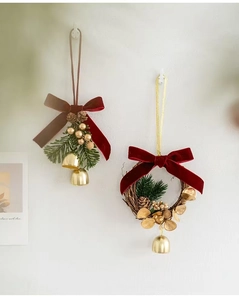 Detail of Christmas pine branch ornaments with golden bells and red velvet bows on a wall
