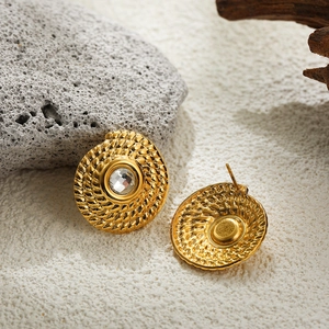Macro detail of gold-plated spiral twist earrings with sparkling center crystal stud