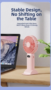 Close-up of pink portable mini fan with digital display on a wooden desk with a laptop.